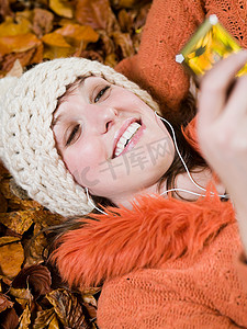 在秋叶上听音乐的女人
