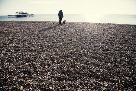 三苏摄影照片_英国苏塞克斯布莱顿布莱顿海滩上布莱顿码头和一名男士和蹒跚学步的女儿的剪影