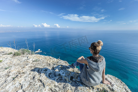 意大利撒丁岛卡利亚里坐在悬崖上眺望海景的年轻女子的背影