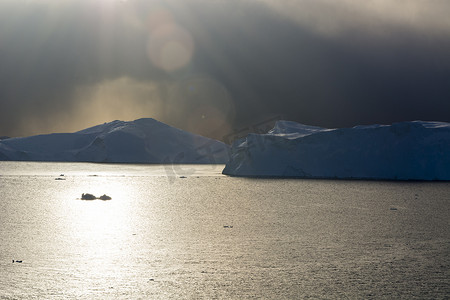 格陵兰岛迪斯科湾伊卢利萨特冰湾冰山上的暴风云和阳光