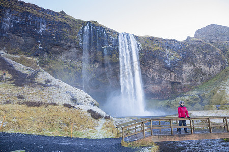 站在桥上的女人看着她身后的瀑布冰岛西南