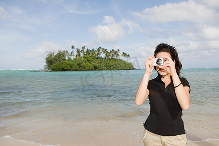 一名女子在海滩上拍照背景是岛屿