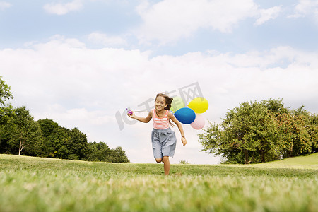 拿着气球在草地上奔跑的女孩