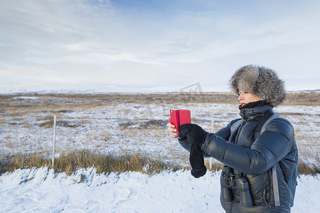 冰岛一名成年女子在积雪覆盖的田野上拍照