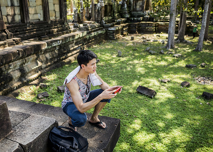 柬埔寨暹粒的寺庙男人蹲着拿着智能手机