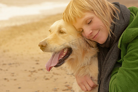 一名女子在海滩上抱着狗