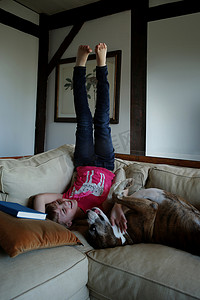 女孩抱着摄影照片_年轻的女孩抱着宠物狗躺在沙发上腿悬在空中