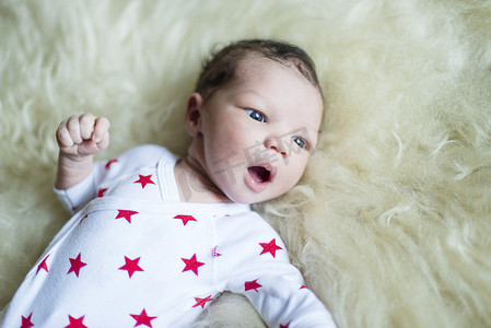 童装上新摄影照片_刚出生的男婴躺在蓬松的毯子上看着别处
