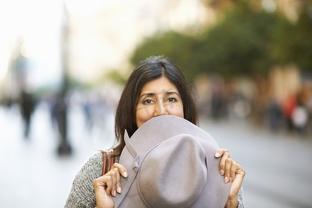 追逐摄影照片_一名妇女在街上戴帽子捂嘴