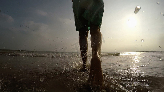 海岸线上的女人在海洋中行走的腿