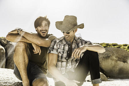 南非开普敦两名男子坐在海滩上大笑