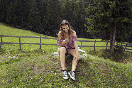 一名年轻女子坐在野外阅读智能手机短信萨特尔贝格姆奥地利蒂罗尔