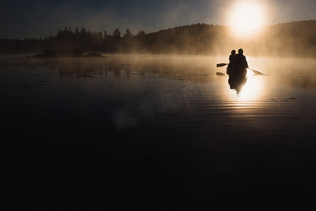 日落时分一对老夫妇在湖面上划独木舟