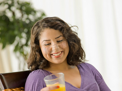 一杯橙汁摄影照片_年轻女子拿着一杯橙汁微笑着