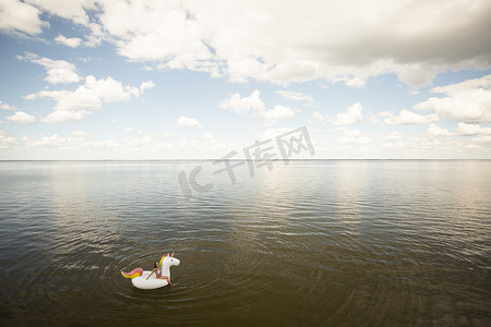 美国佛罗里达州圣罗莎海滩坐在海上充气独角兽上的年轻女子的高角远景