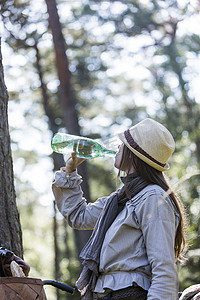 在森林里喝着水瓶的成熟女子自行车手