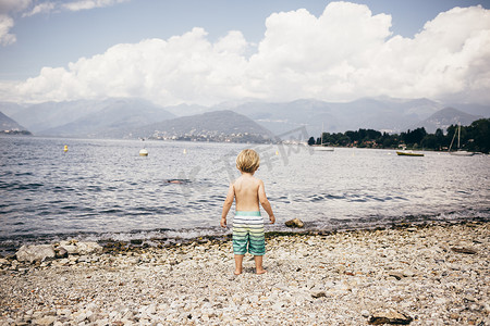 意大利伦巴第路易诺男孩站在湖边的瓦砾海滩上的全身背影