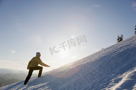 雪山日落摄影照片_一名男子攀登雪山