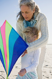 动物和空气摄影照片_祖母和孙女在海滩上放风筝