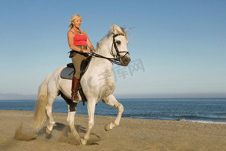 在海滩上骑马的女人