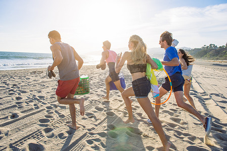 追逐奔跑摄影照片_一群朋友在海滩上奔跑后景