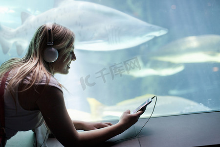 水族馆里戴着耳机听音乐的年轻女子