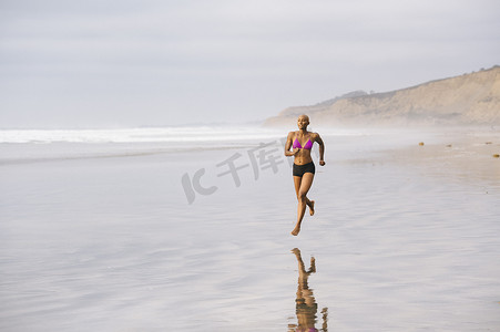 追逐摄影照片_一名比基尼女子在海滩上慢跑