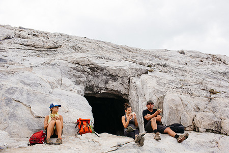 三名徒步旅行者在徒步旅行后休息坐在美国加利福尼亚州红杉国家公园矿物之王洞穴旁
