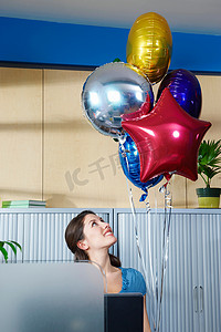 人坐在桌子前摄影照片_年轻女子坐在桌子旁拿着气球