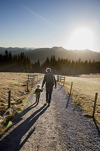 德国巴伐利亚州泰根西男人和蹒跚学步的女儿走在土路上的背影