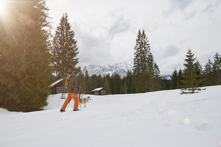 德国巴伐利亚州埃尔茂市一名中年男子穿着雪地鞋穿过雪地狗在身旁