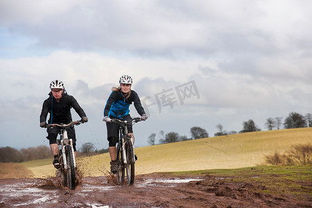 溅泥摄影照片_一对夫妇在泥泞的水坑中骑车