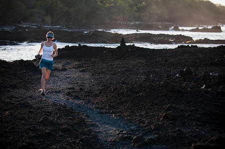 一名女子在岩石海滩上奔跑