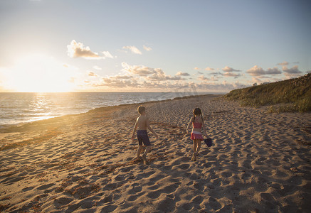 日出时分男孩和妹妹沿着海滩散步美国佛罗里达州朱庇特岛吹石保护区