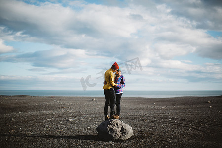 冰岛一对中年夫妇站在巨石上面对面地拥抱在火山景观上