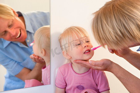 父亲刷牙学步的女儿的牙齿