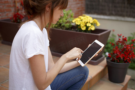 便携式摄影照片_中年妇女坐在户外使用数字平板电脑的侧视