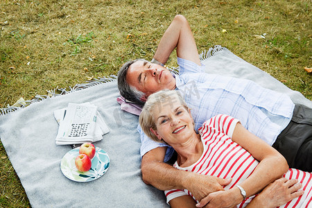 爱情标题摄影照片_一对夫妇躺在草地上的野餐毯子上