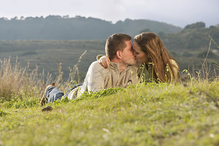 一对年轻夫妇在田野上躺着接吻