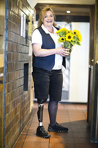 中年妇女戴假肢的肖像站立手持鲜花