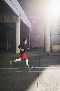 年轻的男性跑步者在阳光明媚的城市地下通道上奔跑