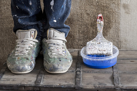 刷鞋摄影照片_脚上穿着脏鞋子旁边是用油漆刷的塑料容器