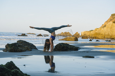 美国加利福尼亚州洛杉矶年轻的女舞者在海滩上做倒立姿势