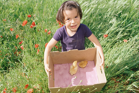 女孩拿着一个纸箱里面装着小鸡