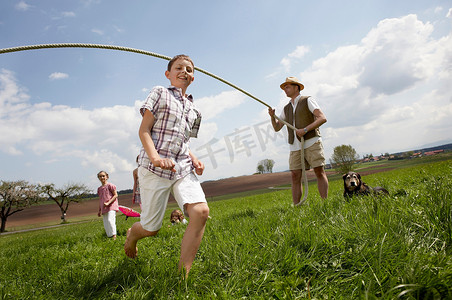 跳绳动作摄影照片_幸福的家庭在乡下跳绳