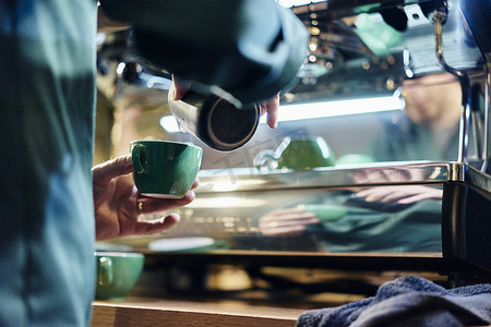 剪影咖啡杯摄影照片_咖啡店男咖啡师将牛奶倒入杯子的剪影