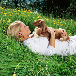 一名妇女抱着狗躺在田野上