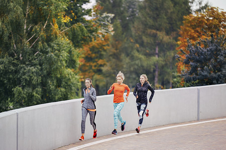 三名女跑步者沿着公园路跑步