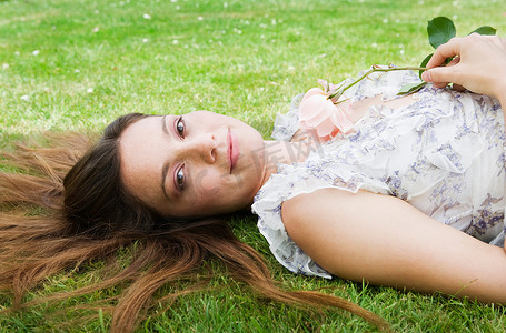 玫瑰家族摄影照片_女人躺在草地上手里拿着玫瑰