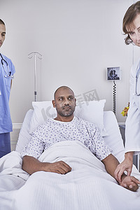 性病摄影照片_医生为躺在医院病床上的病人把脉